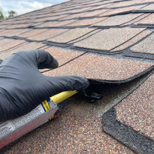 contractor applying ahesive to roof shingle noble ok